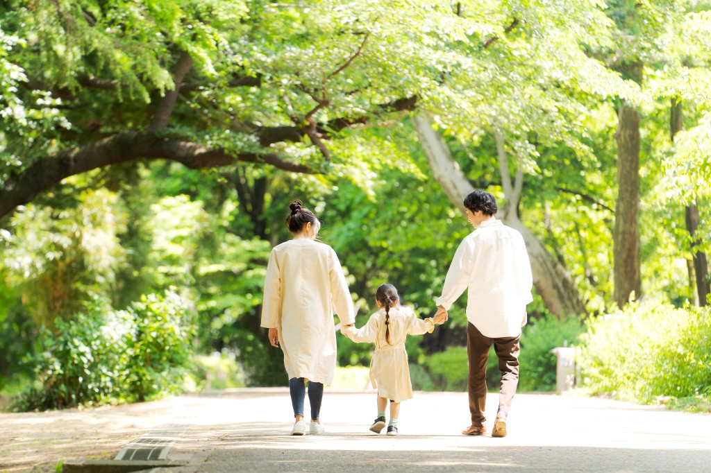 緑豊かな公園を歩く家族