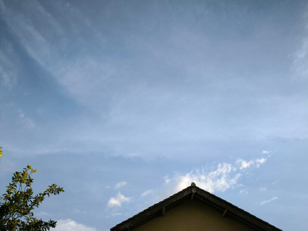 三角屋根の一戸建てを下から見上げた外観、青空
