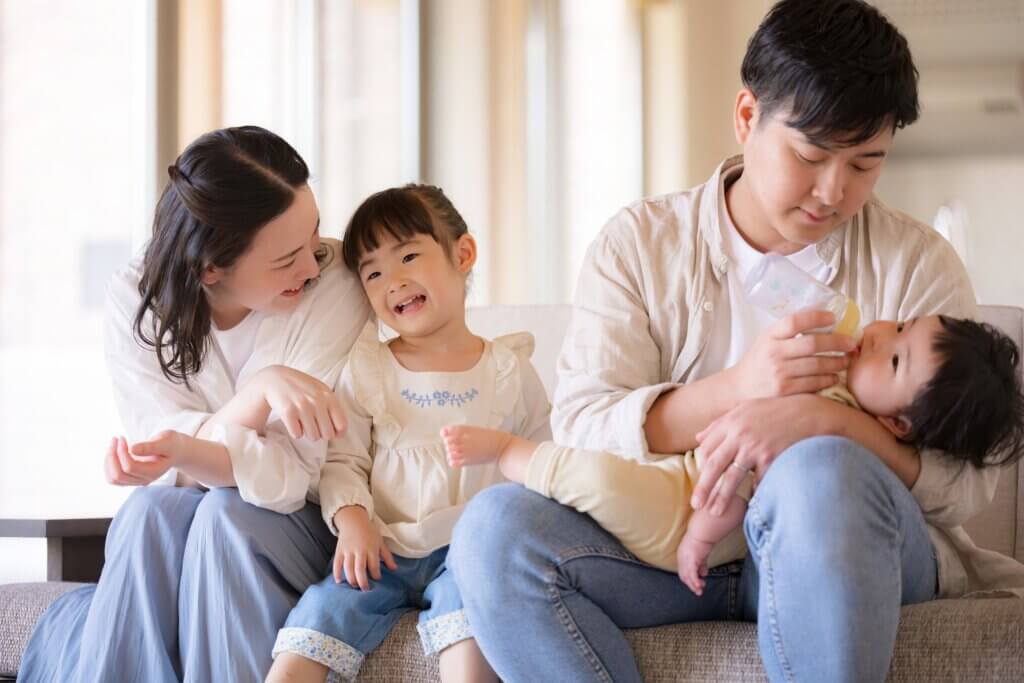大きな窓のある明るいリビングでくつろぐ日本人家族、引き