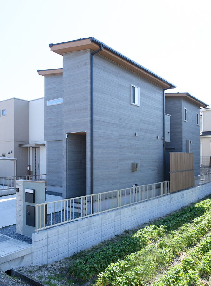 道路側を閉じたダーク色の外壁の2階建て