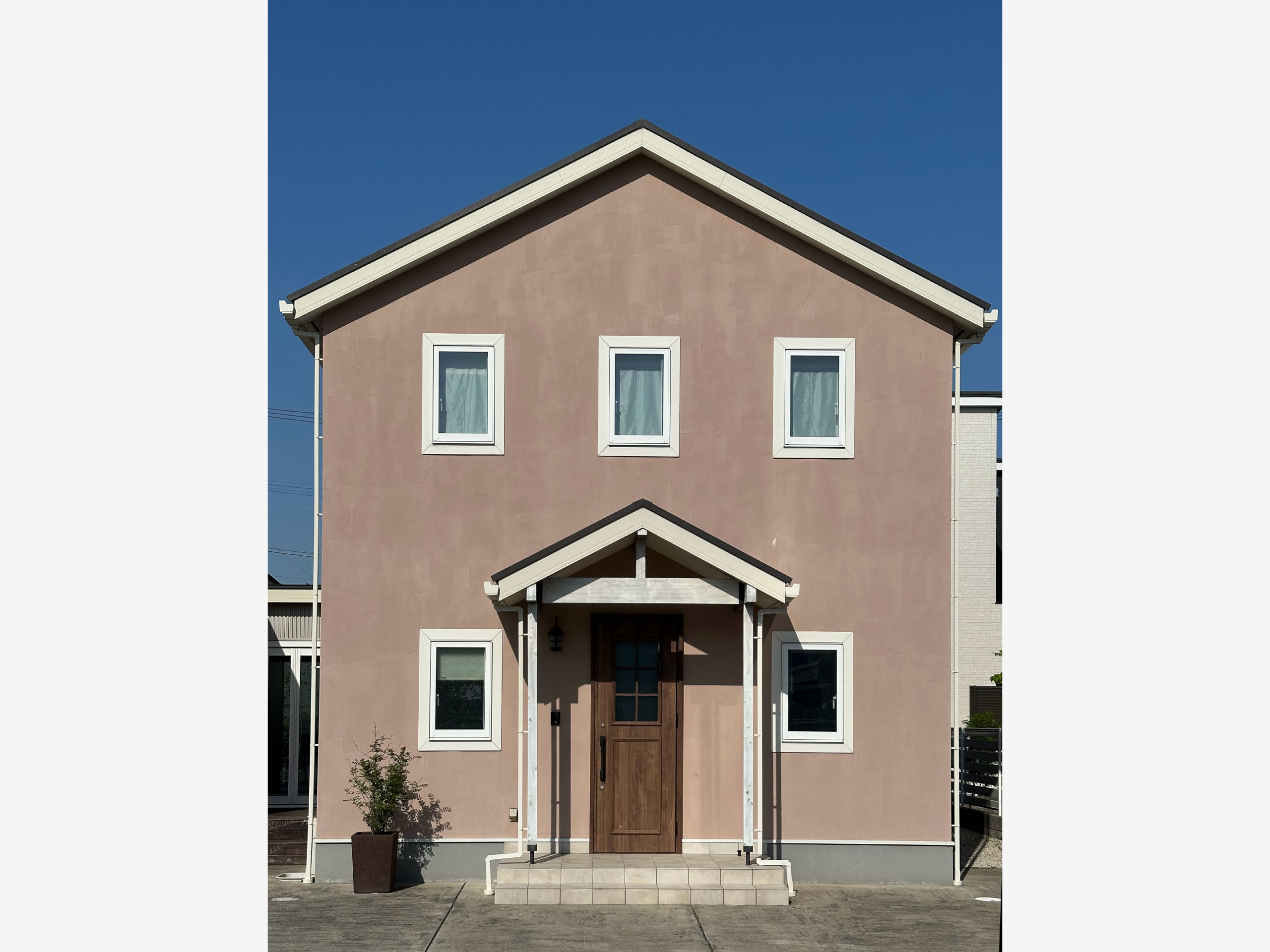 佐賀展示場の外観。淡いピンクの塗り壁と切妻屋根