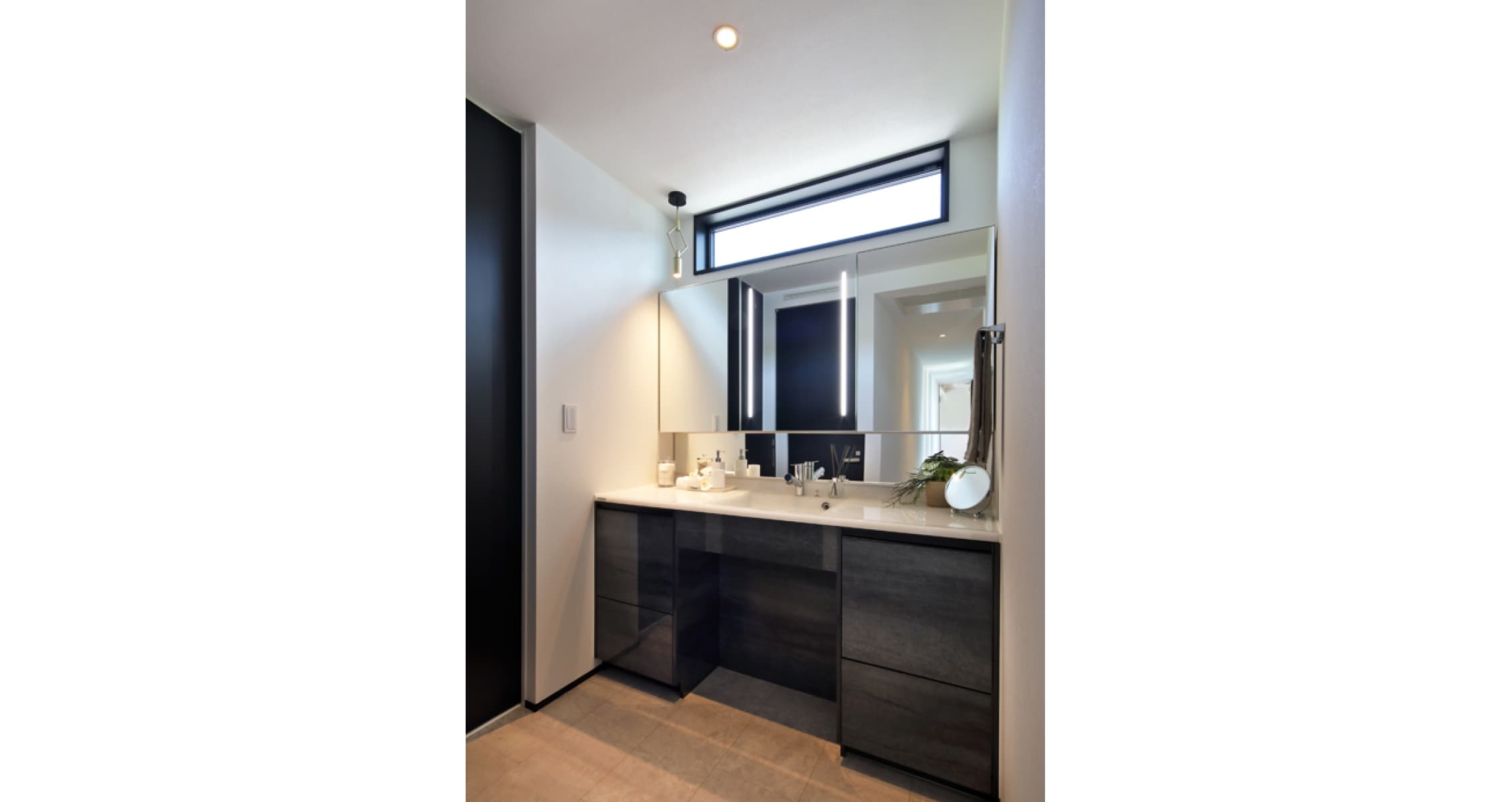 福井 家の森展示場の洗面室。黒木目の洗面台と大きな鏡